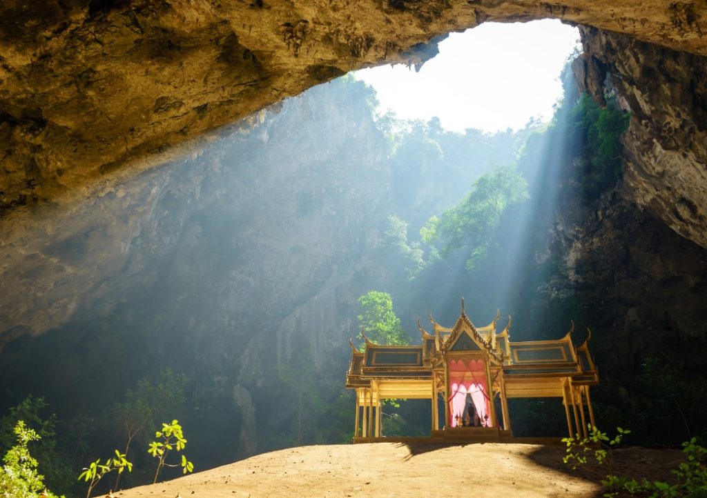 A pavilion hidden inside a cave with an opening above shining light through