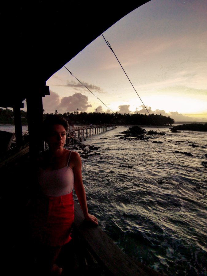 The sun setting from behind a cluster of palm trees at Cloud 9 Siargao