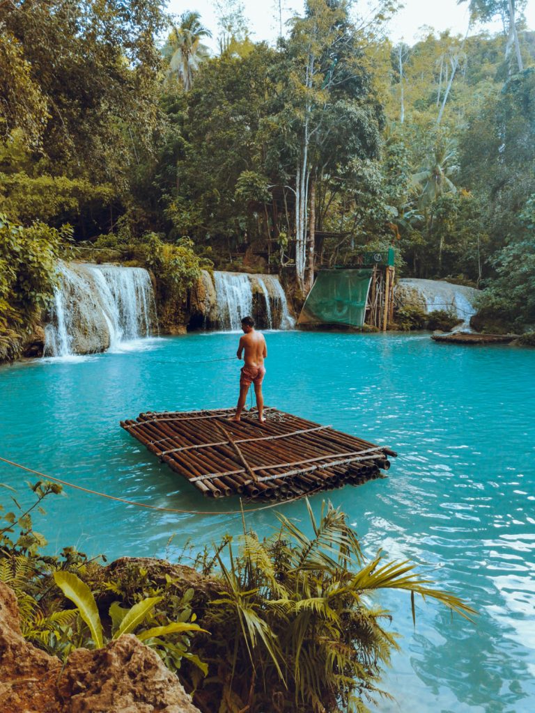 Pulling myself under the cascade while trying to balance myself on a bamboo barge