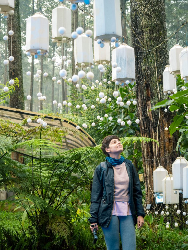 Jacqueline posing under a bunch of white lantern hanging from the trees