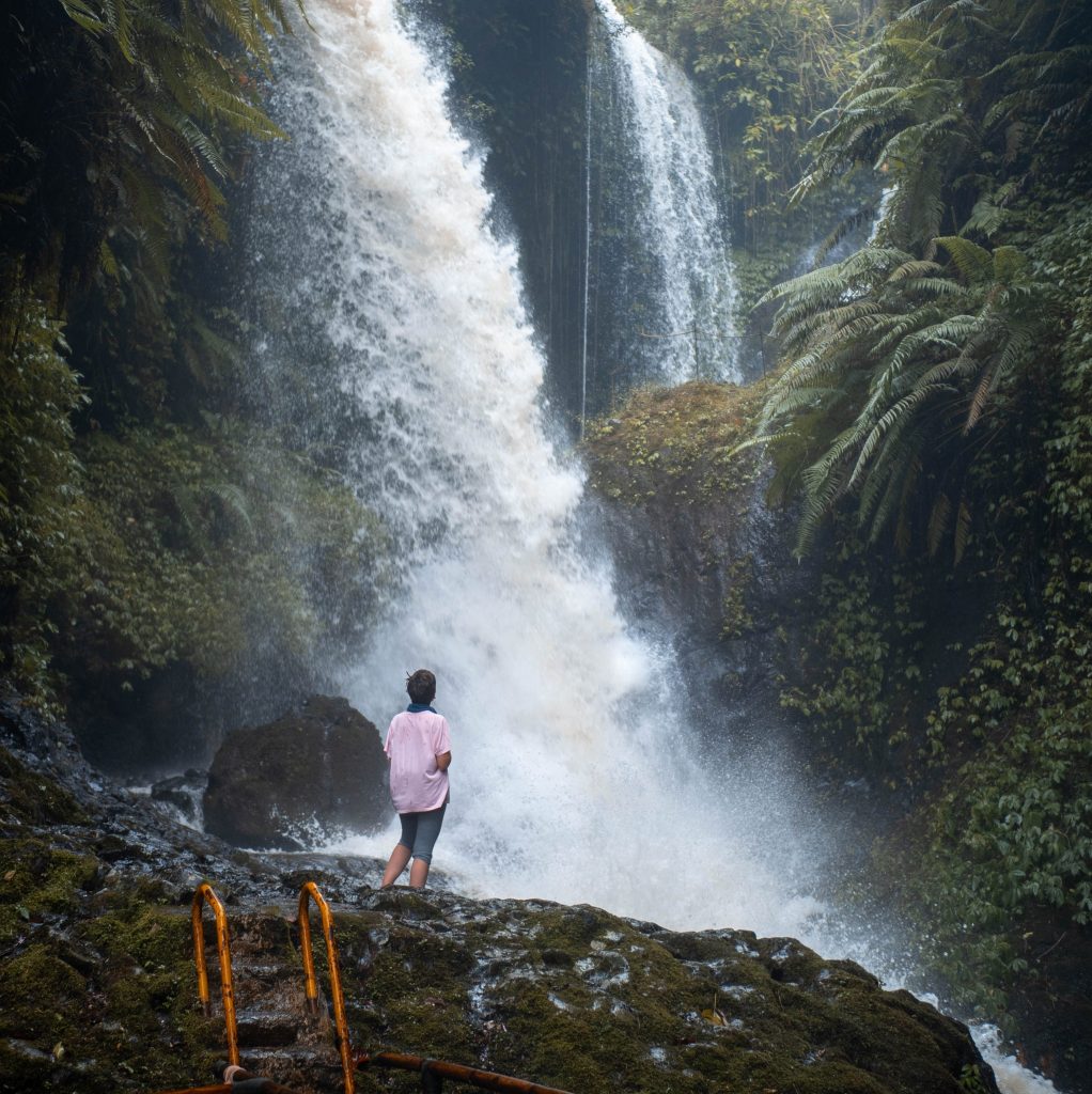 Jacqueline Standing near a raging cascade in canyon inside the jungle