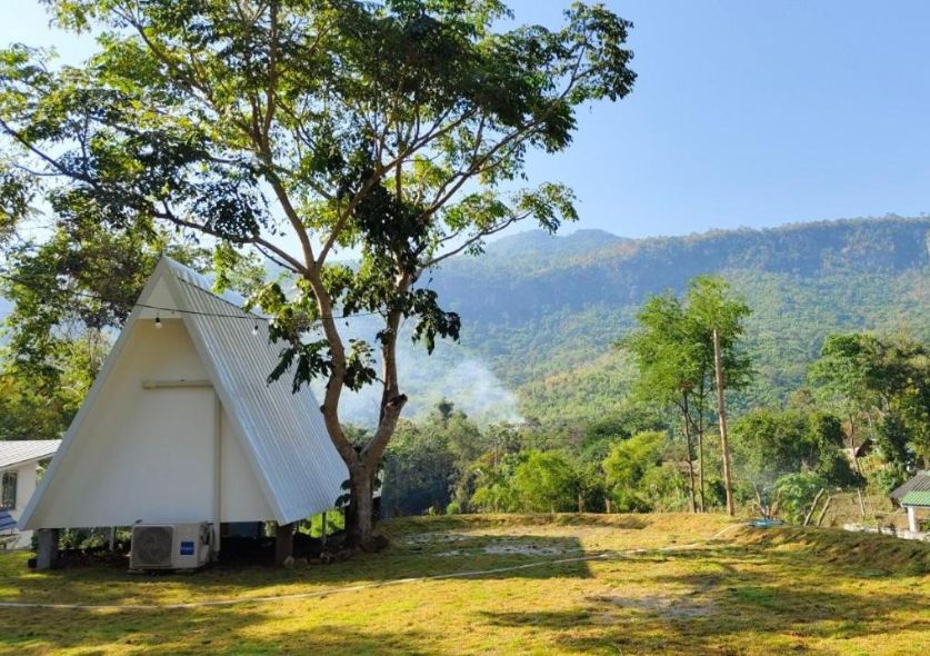 A fancy camp perched on a mountain overlooking a lake and jungle.