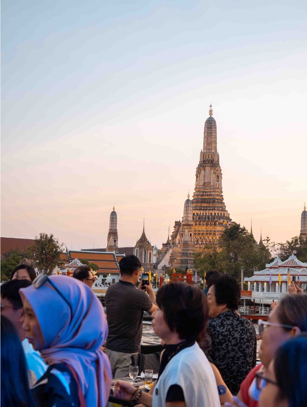 People dancing on the Chao Phraya river sunset cruise and Wat Arun in the Background