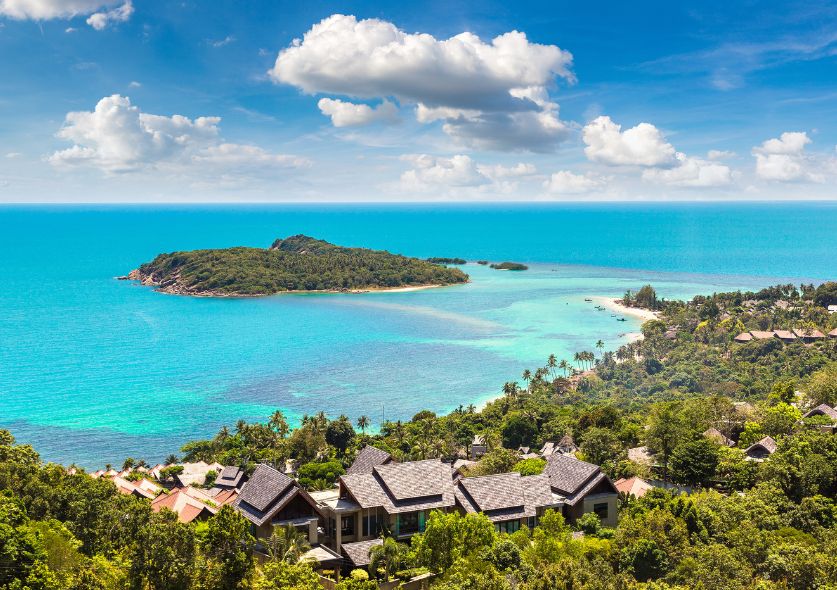 A small island covered in trees and surrounded with clear tropical waters in Koh Samui Thailand