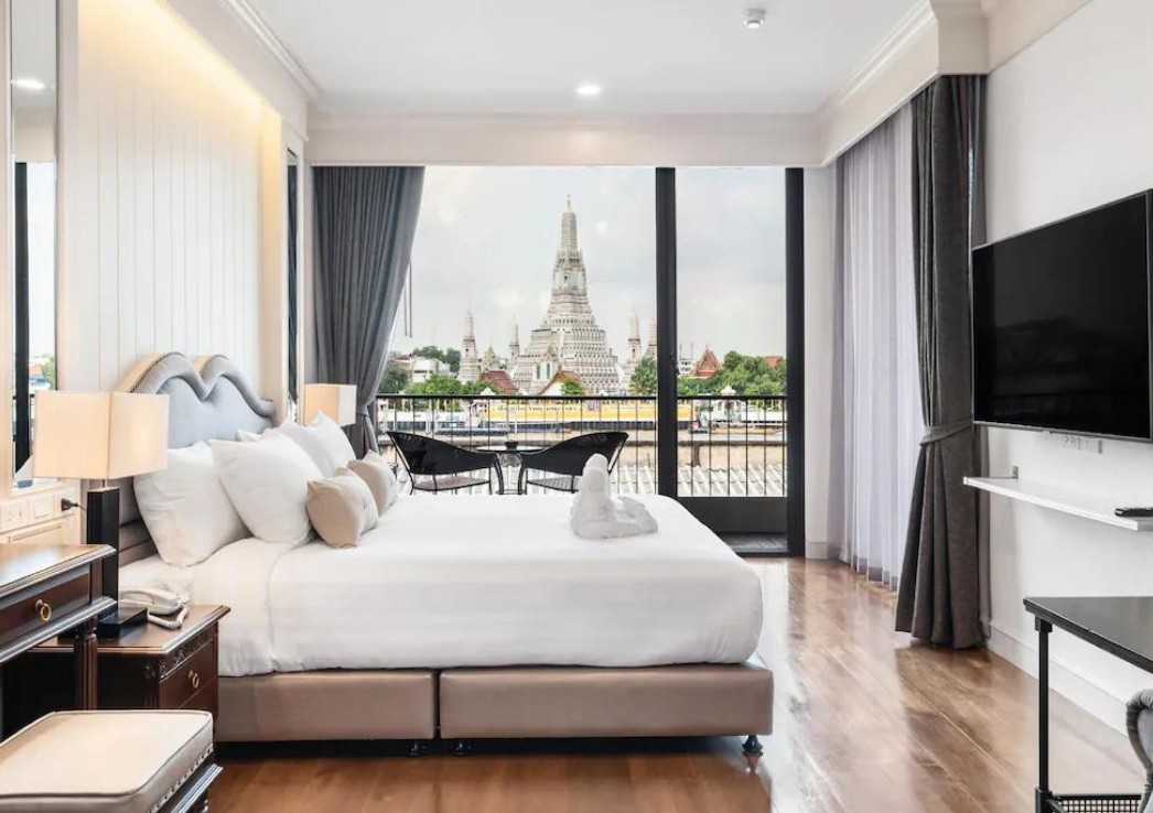 A hotel room with floor to ceiling window and a temple outside