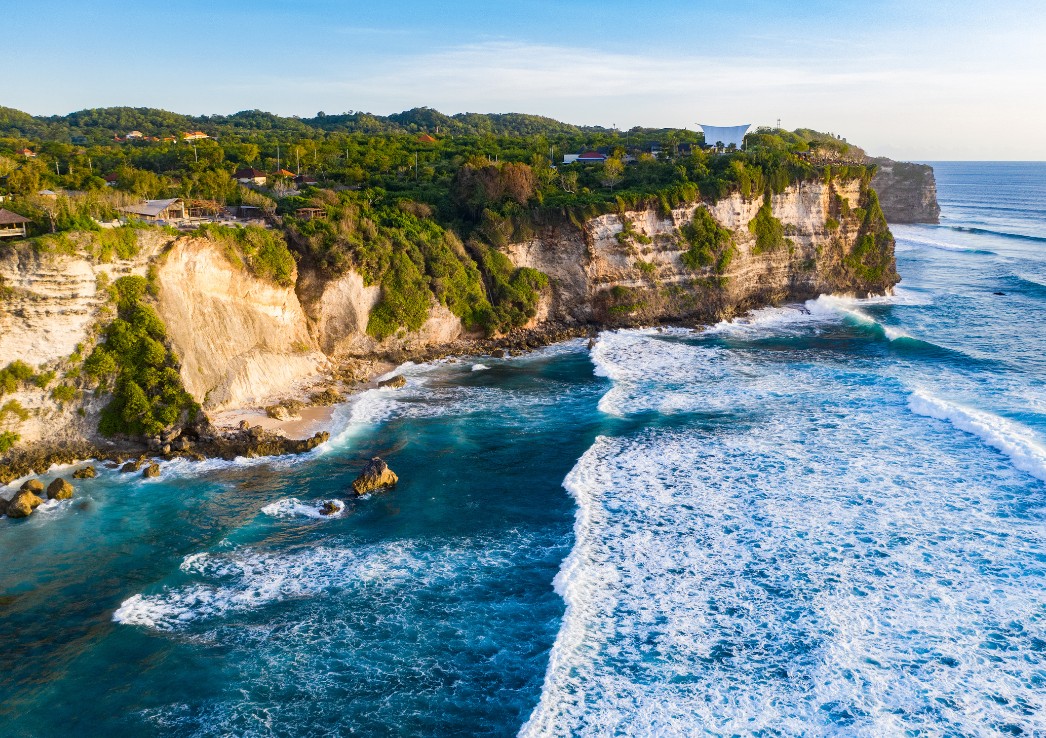 A view of cliffs in Uluwatu Bali with crashing waves beneath
