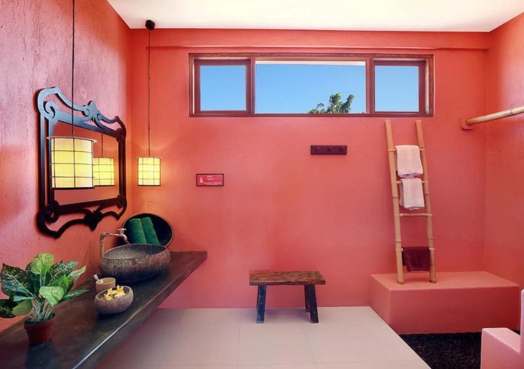 A bathroom with pink walls and vintage sink and a wooden ladder