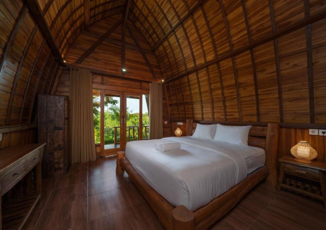 Where to stay in Uluwatu. A wooden cottage form inside with a bed with white sheets