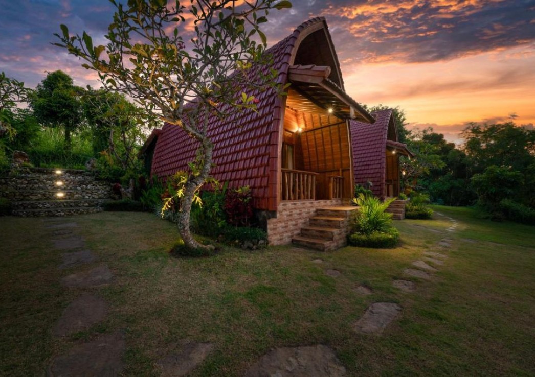 A dimly lit cottage at dusk in the middle of a garden