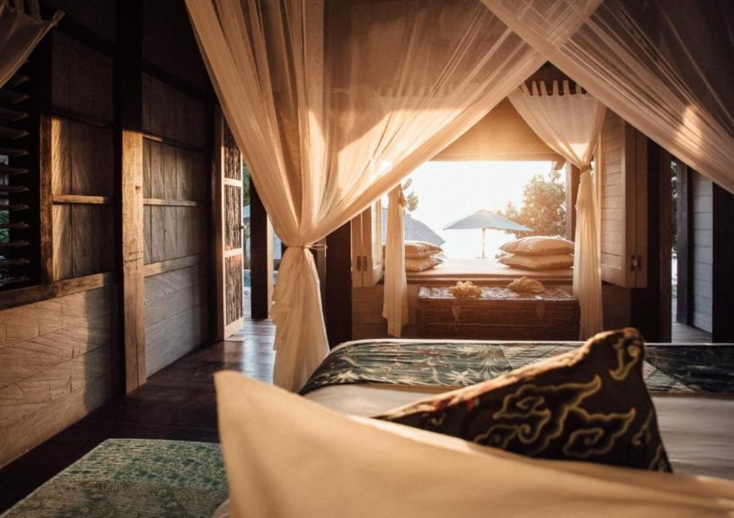 A POV shot from a suite over looking the ocean and the bed in the foreground