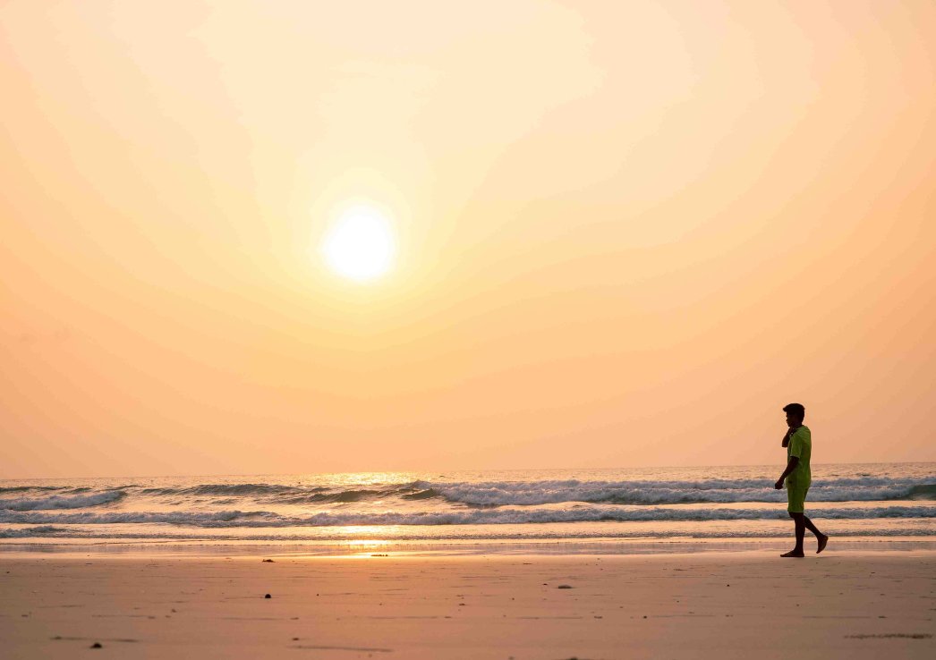 A silhouette of a man walking along a beach at sunset in Koh Phangan Haad Rin